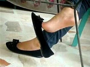 Sexy Füße, die mit schwarzem Flachschuh baumeln